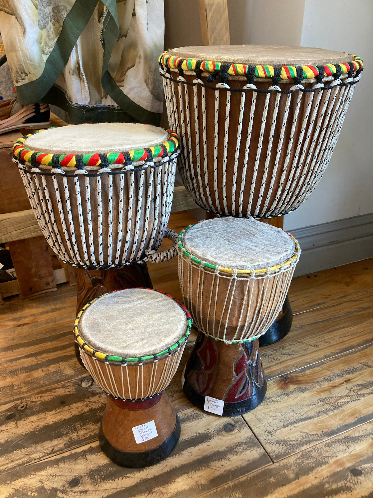 Teranga Africa/Choose Senegal hand-carved wooden djembe drums with goatskin heads and colorful braided cord trim.